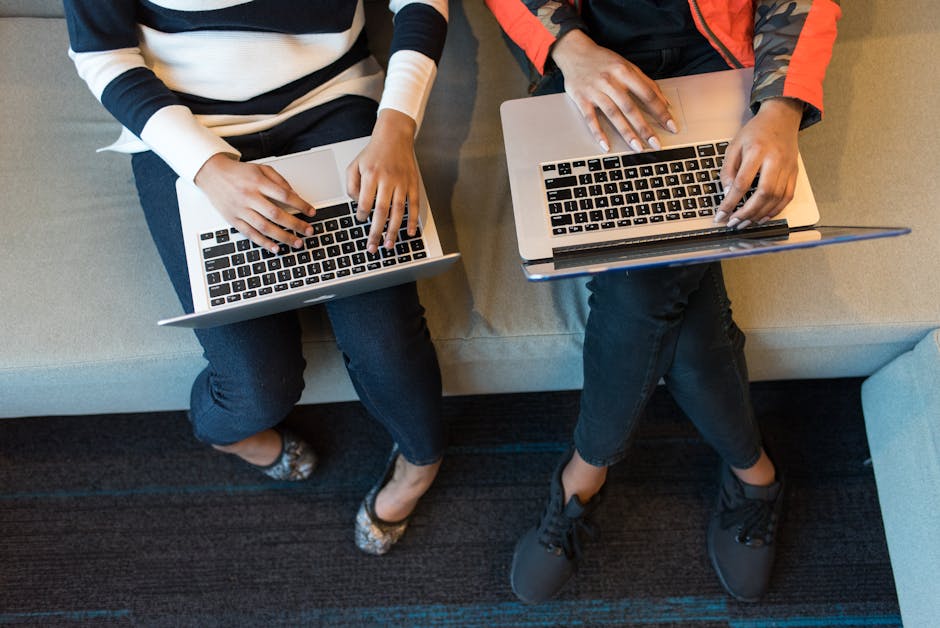 Two people working on laptops from above, showcasing collaboration in a tech environment